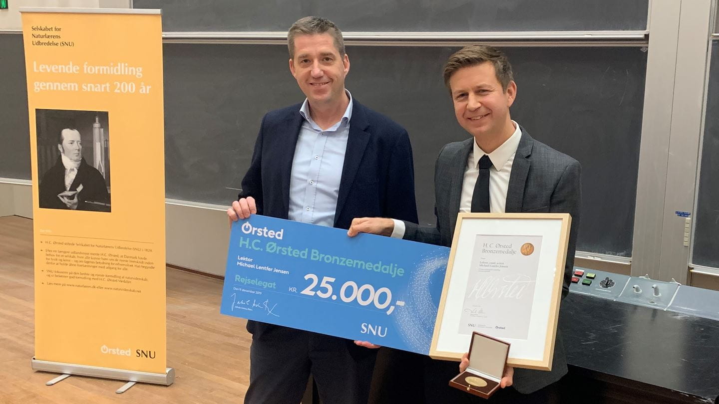 Medaljemodtager Michael Lentfer Jensen (til højre) får overrakt rejselegatetet af Jesper Skov Gretlund fra Ørsted.