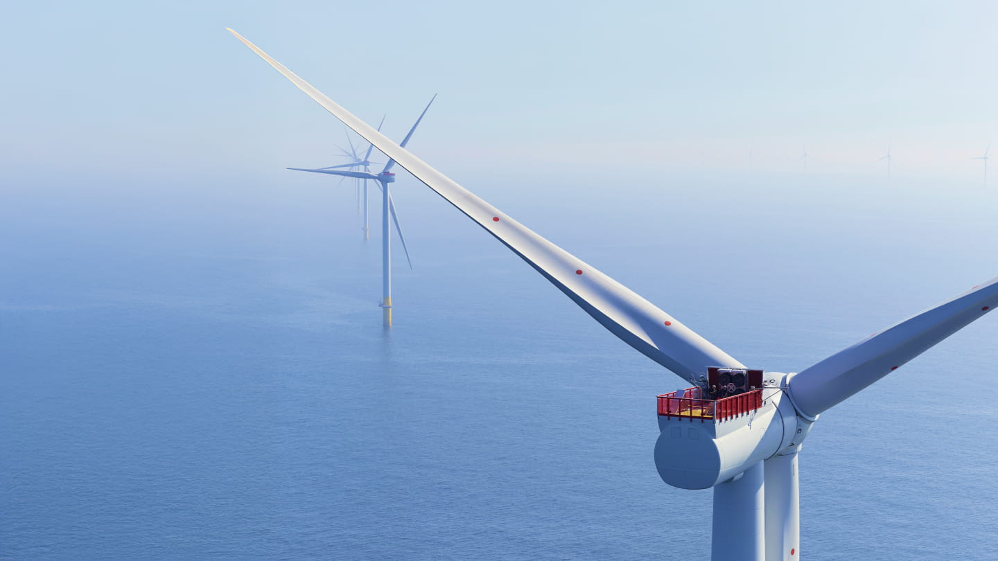 Close-up of an offshore wind turbine nacelle and rotor above the sea, with other turbines in the distance