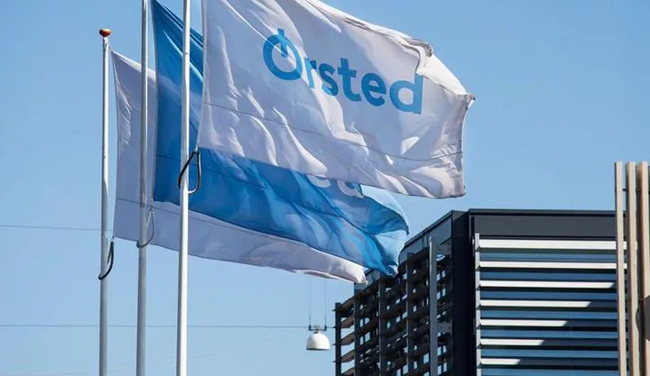Three Ørsted flags waving outside of an Ørsted office on a sunny day.