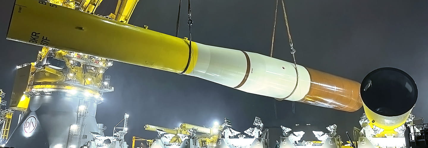 An offshore wind turbine tower being lifted during wind farm construction