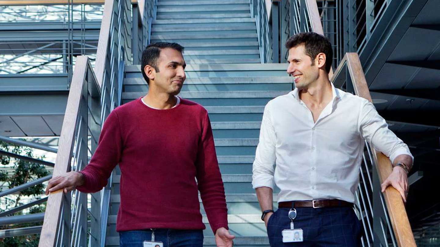 Two employees walking down a flight of stairs side by side.