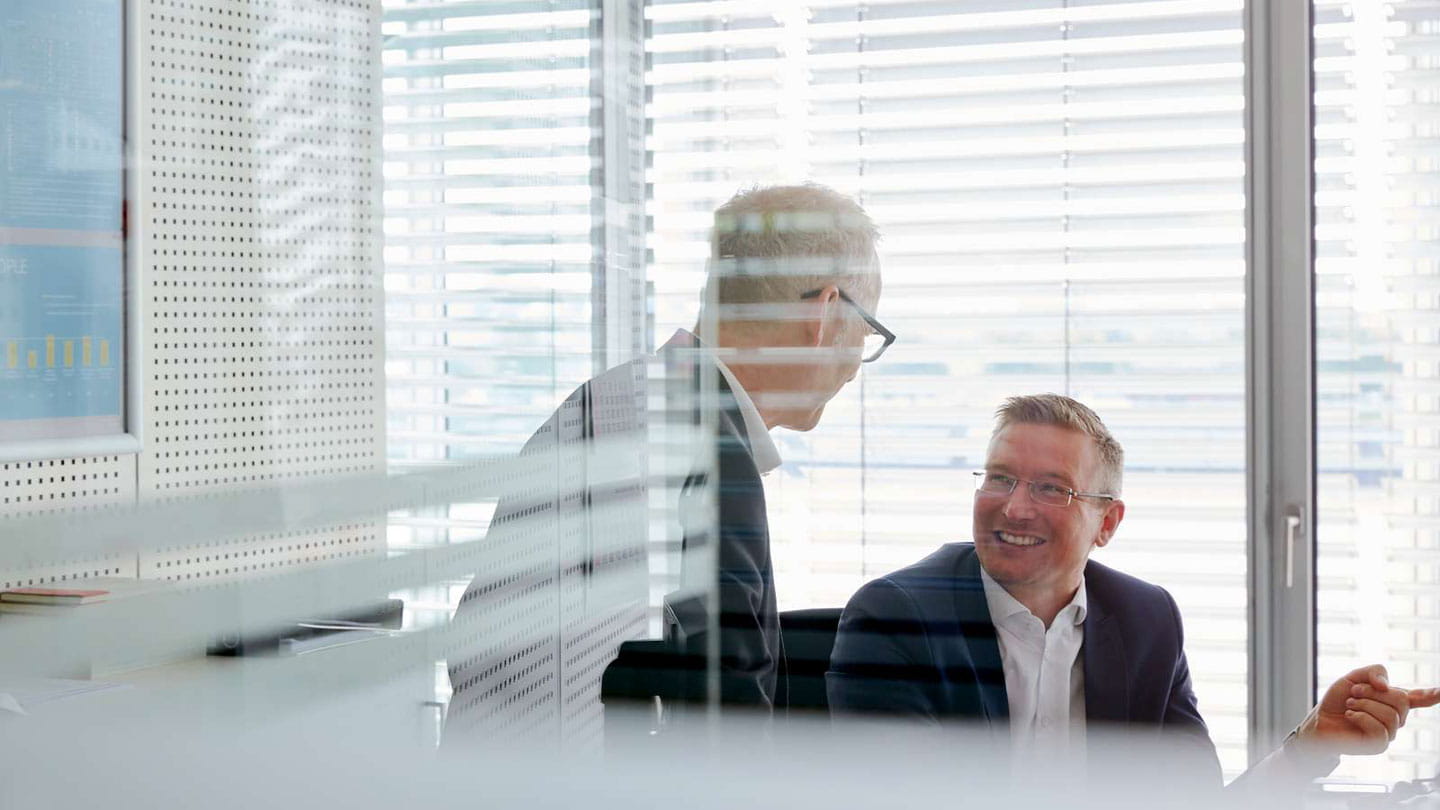 Two happy employees seen through window