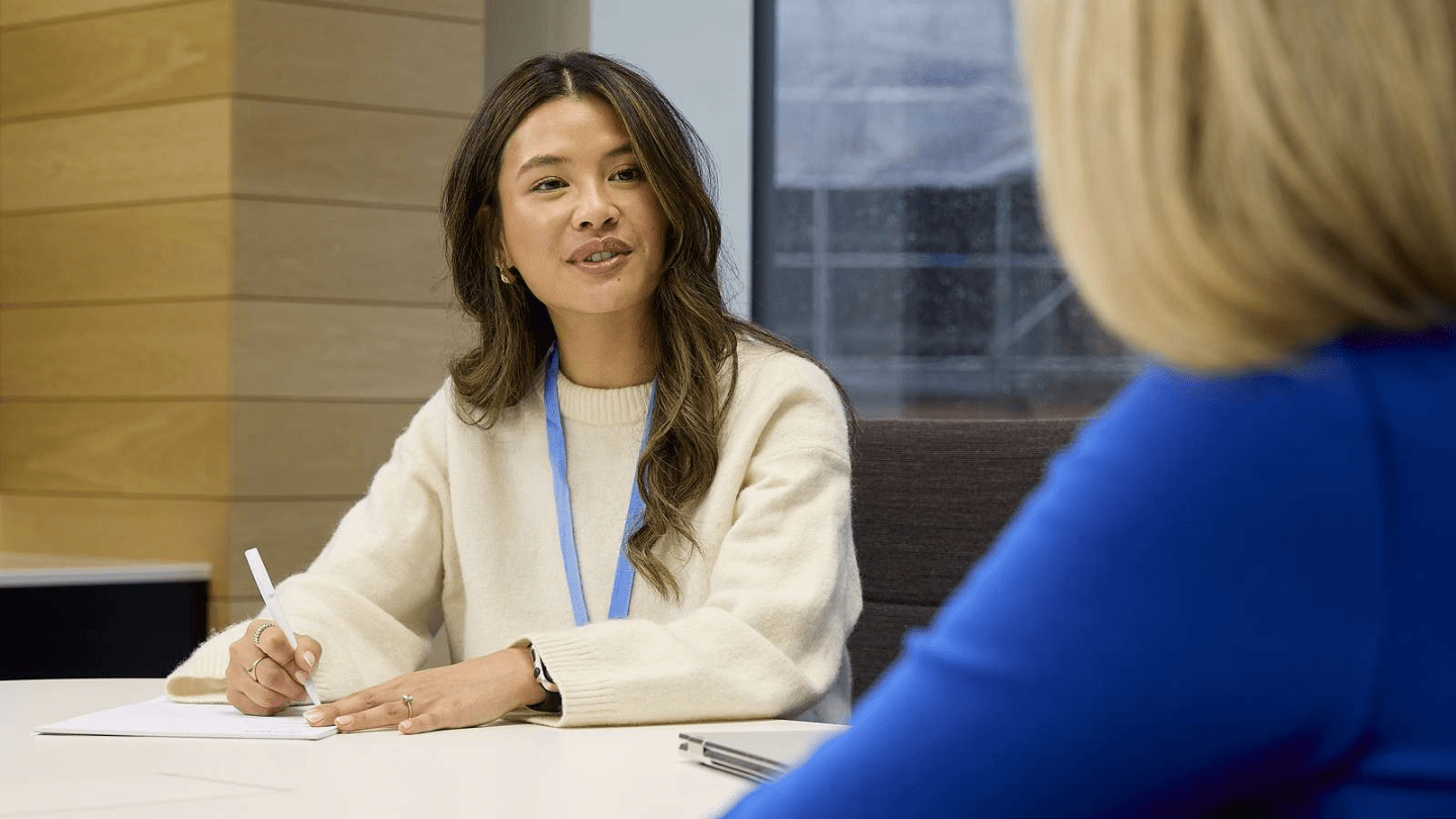 Portrait of employees in London Office. Meeting room table, talking, pen, paper, window
