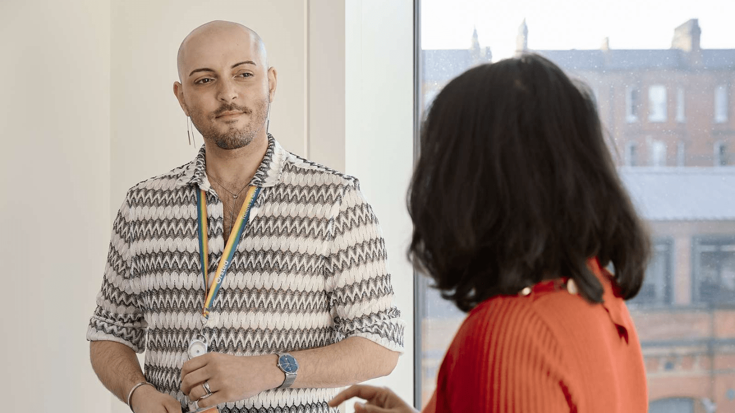 Portrait of employees in London Office. Standing chatting, smiling, window view