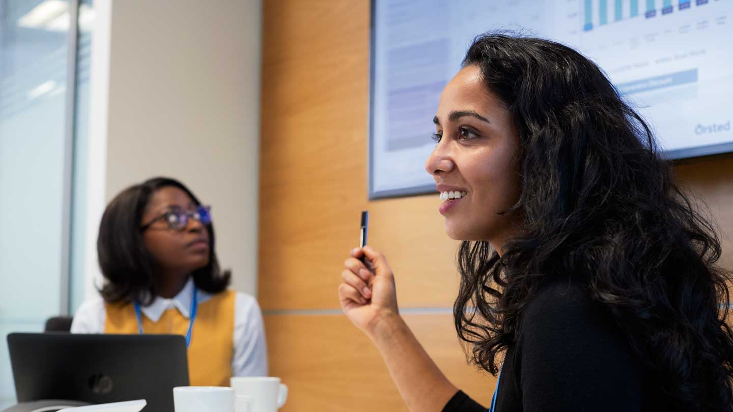 Woman presenting while colleague listens.
