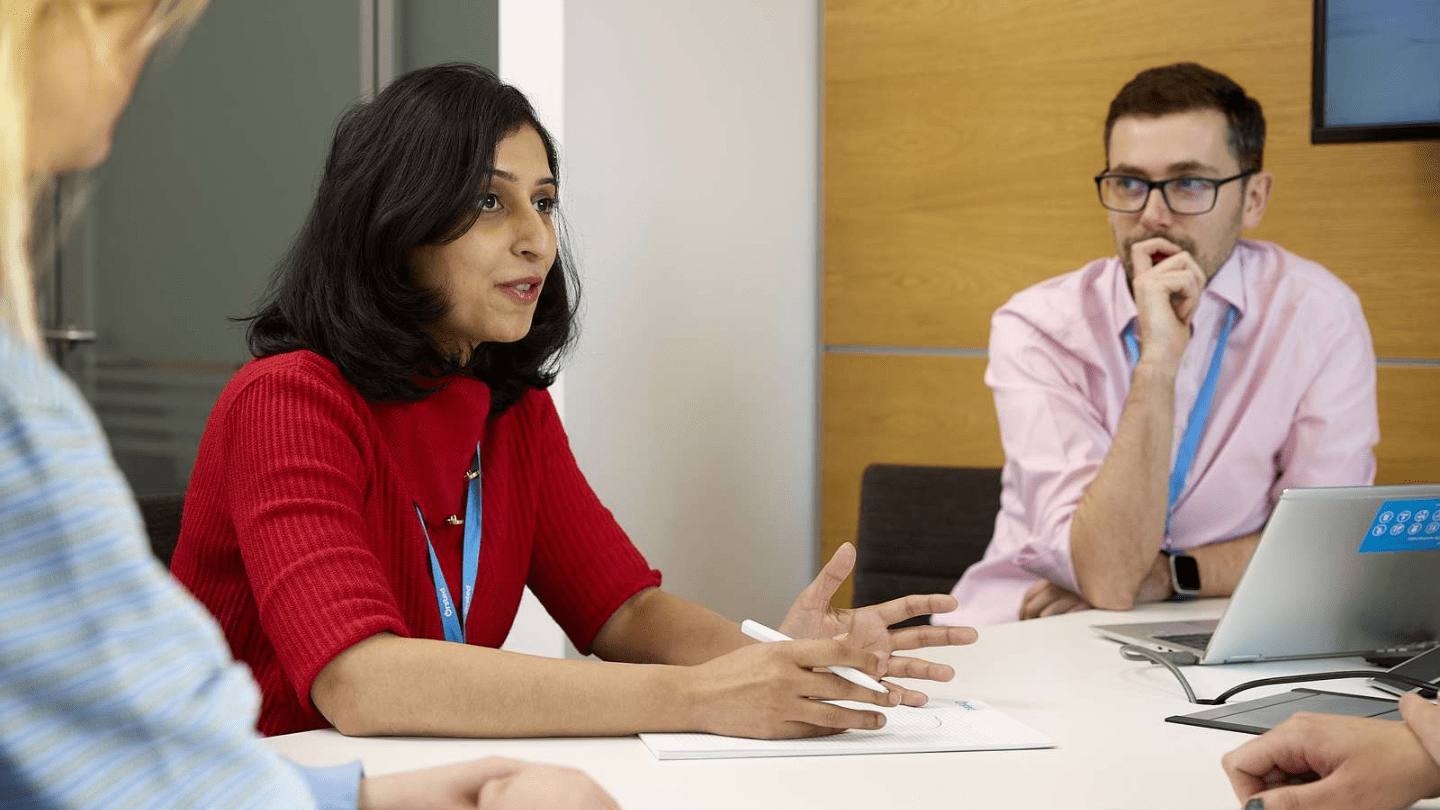 Portraits of employees in London Office. Sitting in a meeting room, table, talking, smiling
