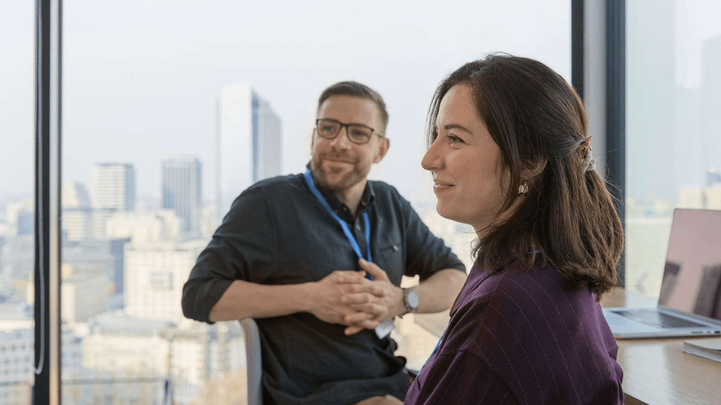 Poland office. Employees sitting by the window smiling.