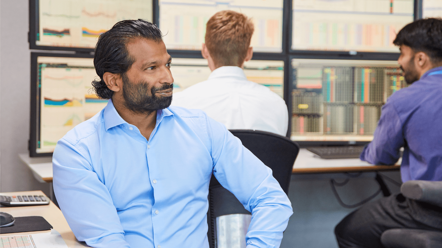 Power trader at trading desk smiling.