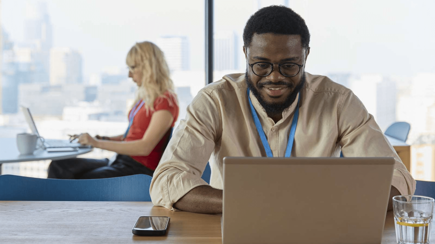 Poland office employees sitting at two tables with laptops, working and smiling