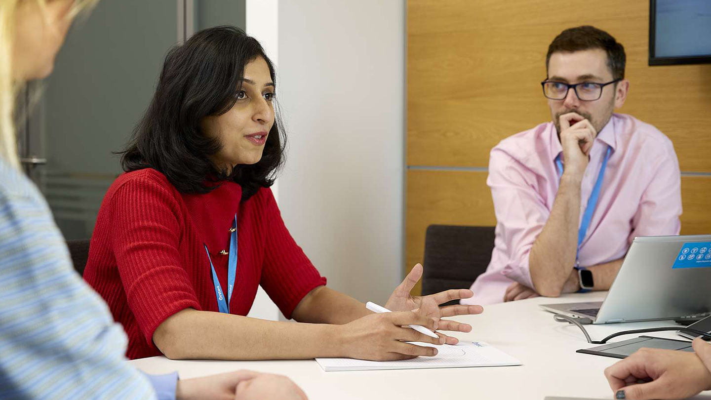 Colleagues discuss project plans in an Orsted meeting room with notes and a laptop.