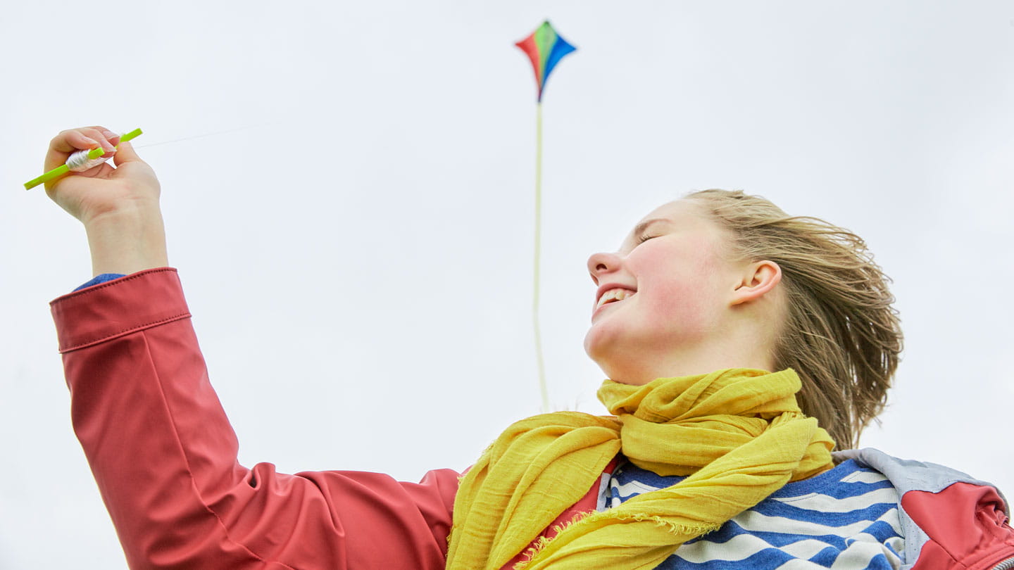 girl laughing outside while flying kite
