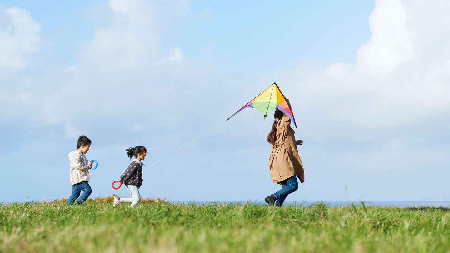 Tres niños corriendo en un parque preparándose para volar una cometa. 