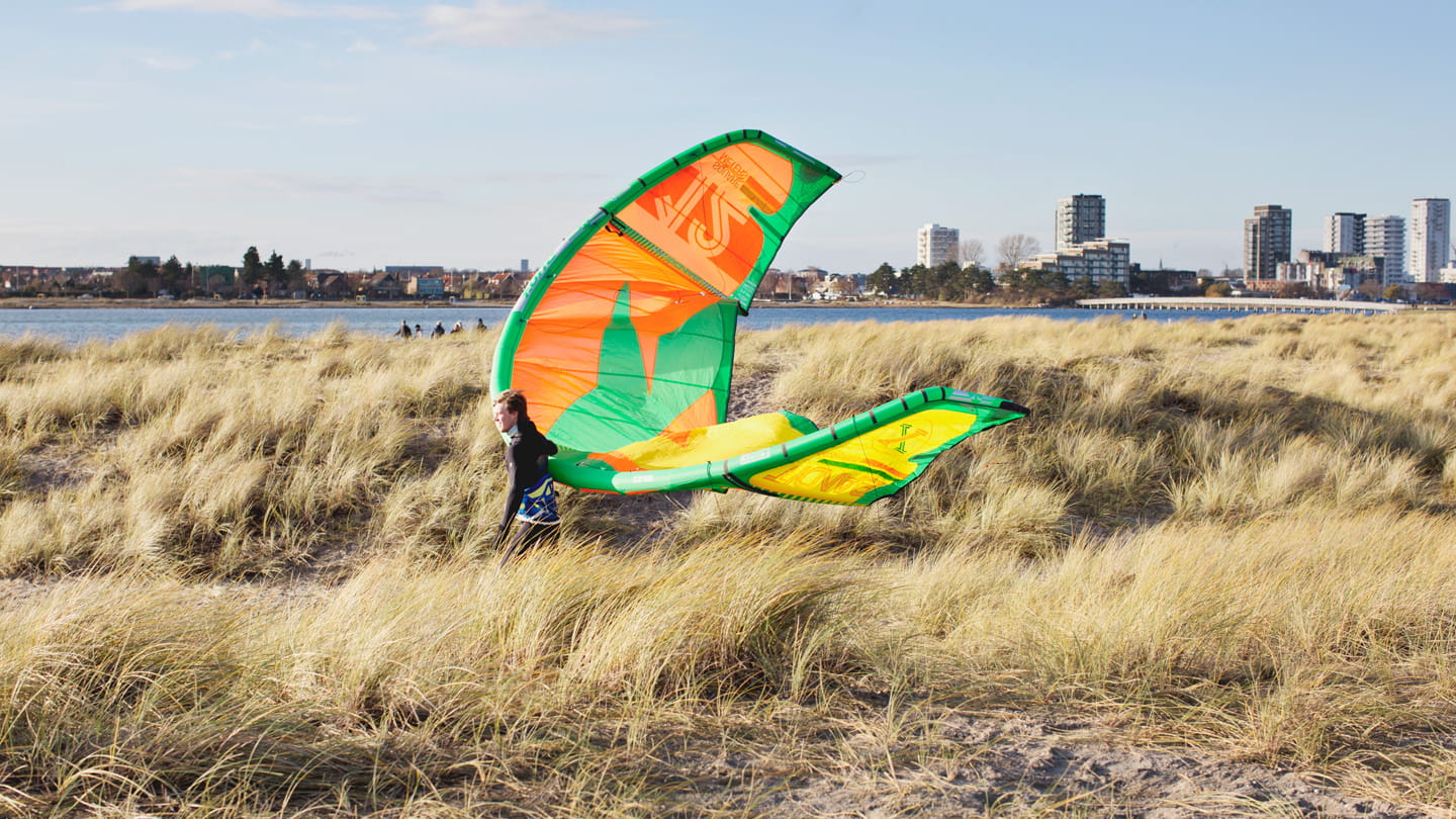Surfer walking through dunes at Amager beach