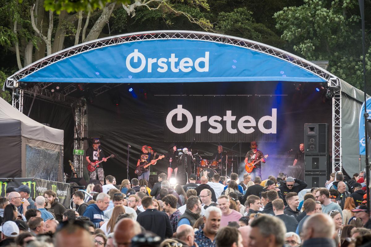 Image shows a music band playing on a stage at the Bushy's TT event in the Isle of Man.  Ørsted's logo is displayed at the top of the staging