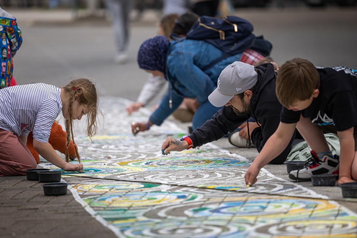 A group of children creating a chalk drawing of a wind turbine blade in Grimsby
