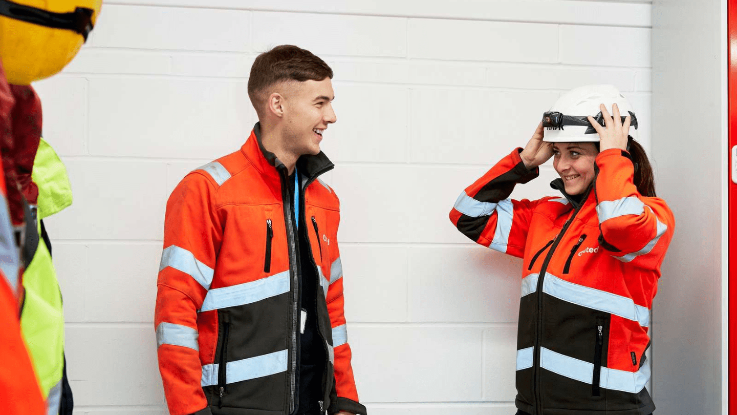 Smiling people in Orsted jackets and helmets