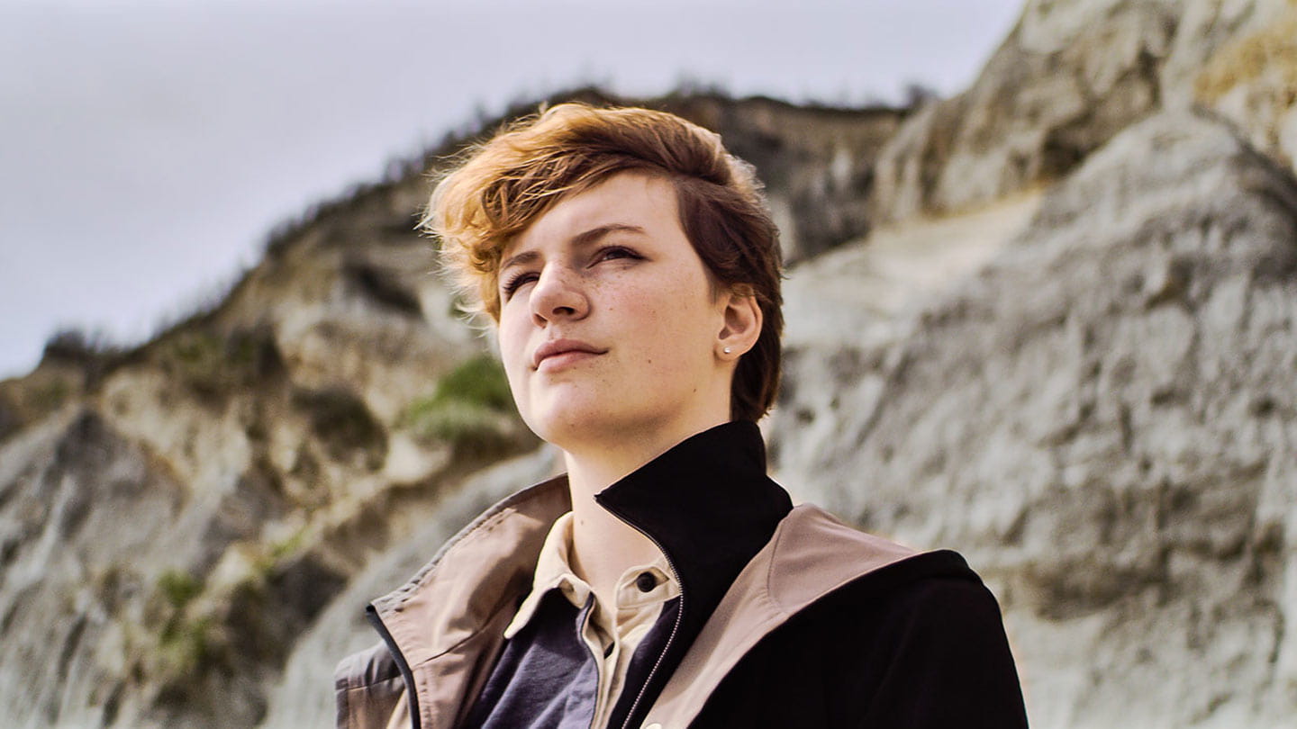 Amira Wilson, environmentalist, student, and offshore wind supporter, stands by the cliffs on Block Island's beach.
