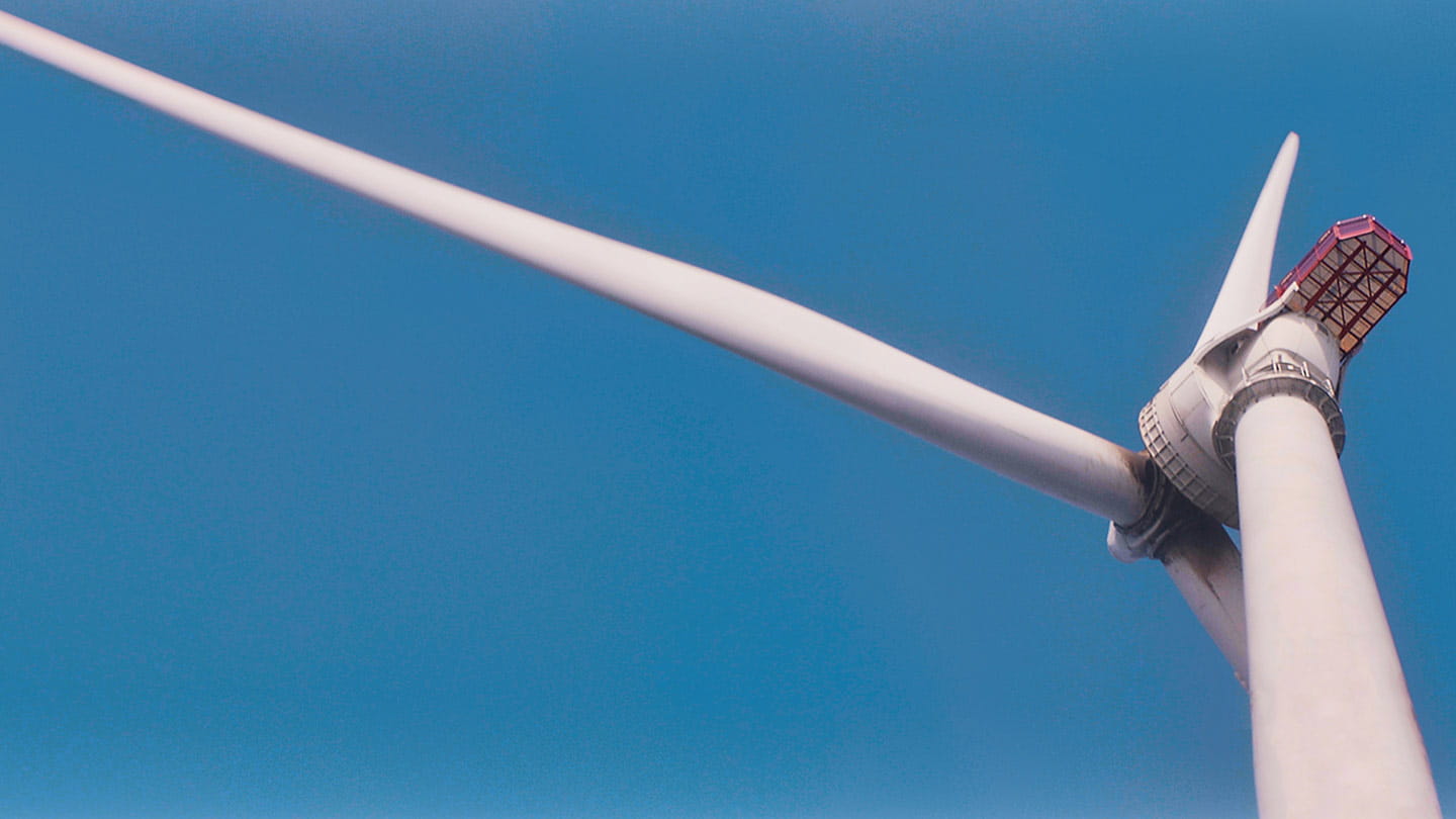 The hub and blades of an offshore wind turbine seen from below, showing how offshore wind becomes clean, reliable energy.