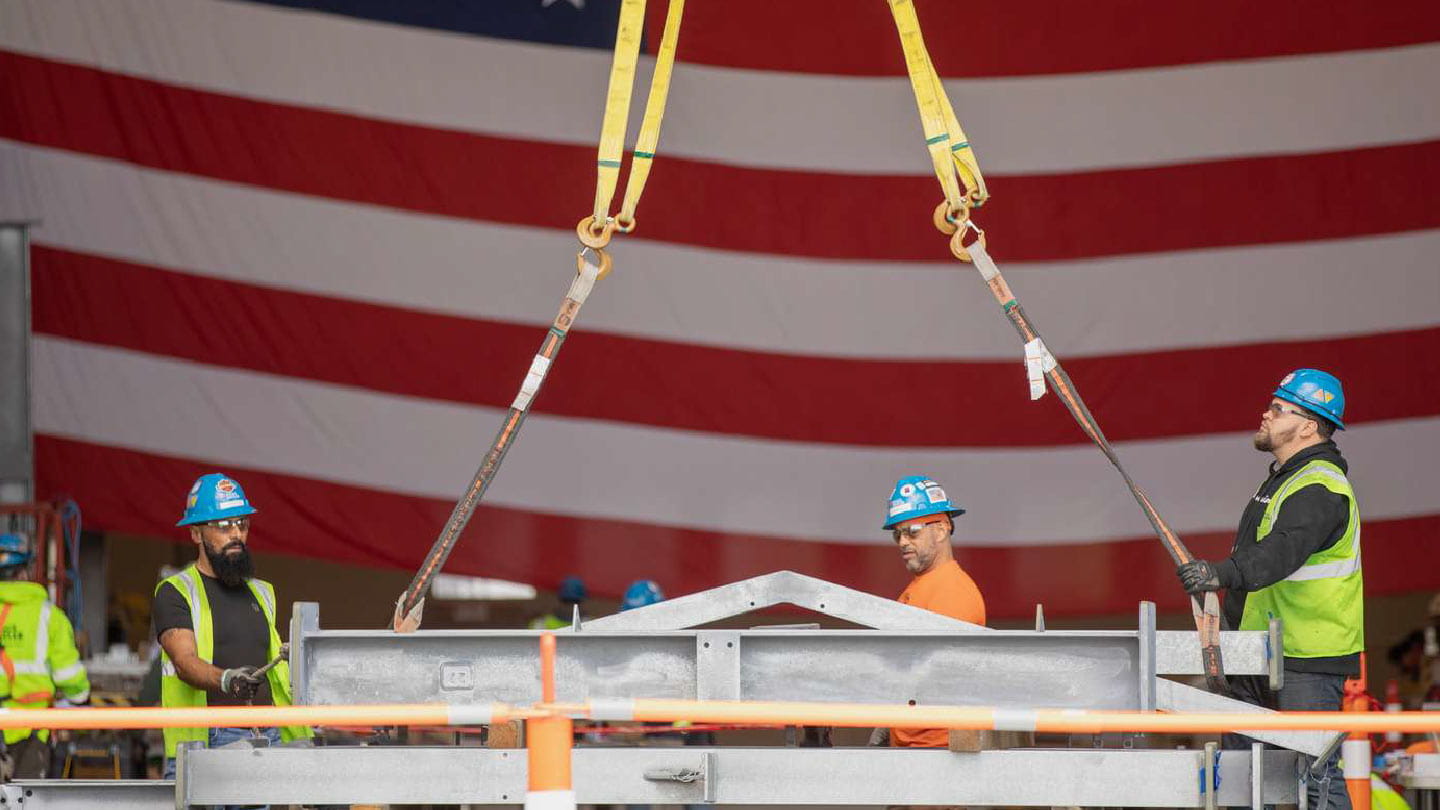 Well-paid union workers hoist equipment in front of an American flag as part of Ørsted’s National Offshore Wind Agreement 