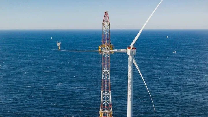 A red and yellow crane constructing an Ørsted offshore wind turbine, showing how to build an offshore wind farm.