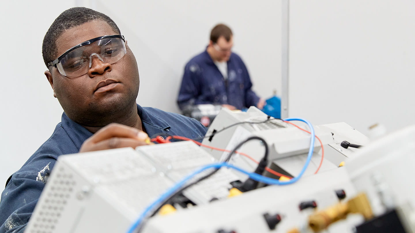 Two male trainees working on wind turbines as part of an offshore wind workforce development program supported by Ørsted.